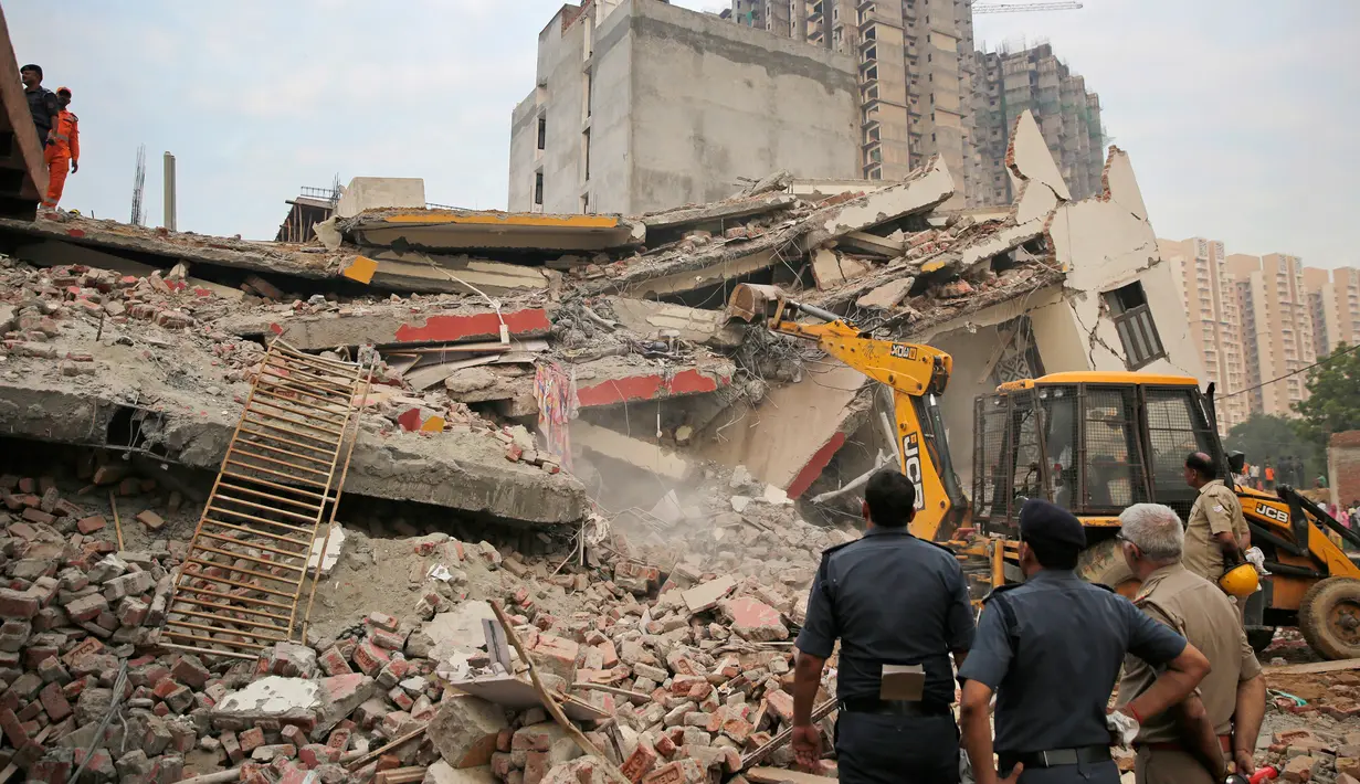 Petugas menggunakan alat berat mencari korban yang terjebak reruntuhan gedung ambruk di desa Shahberi, pinggiran New Delhi, India, Rabu (18/7). Setidaknya 100 orang dikerahkan untuk mengangkat reruntuhan. (AP Photo/Altaf Qadri)