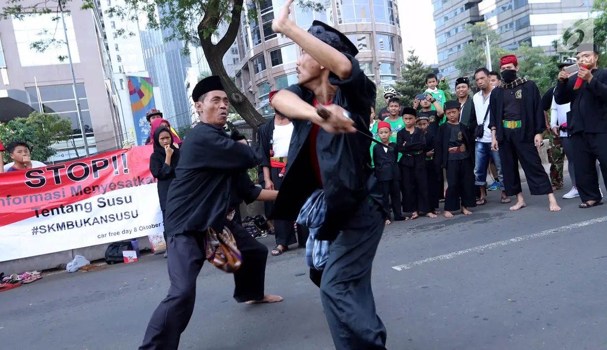 Dua pendekar saling unjuk kebolehan di hadapan warga saat Car Free Day di kawasan Senayan, Jakarta, Minggu (8/10). Aksi ini untuk melestarikan olahraga pencak silat Betawi. (Liputan6.com/Fery Pradolo)