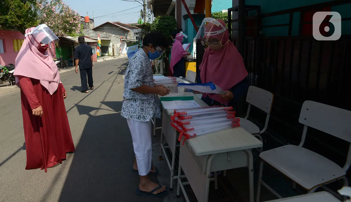 Guru SDIT Ibnu Sina memberikan tugas sekolah secara drive-thru kepada wali murid di Jakarta, Rabu (26/8/2020). Selama pembelajaran jarak jauh, siswa diwajibkan mengambil dan mengembalikan tugas di sekolah. (merdeka.com/Imam Buhori)