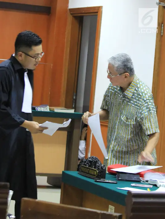 Terdakwa kasus mafia tanah Muljono Tedjokusumo berdiskusi dengan kuasa hukum saat menjalani sidang di PN Jakarta Barat, Rabu (5/12). Sidang menghadirkan saksi mantan Lurah Kedoya Selatan dan 2 mantan staf. (Liputan6.com/HO/Farid)