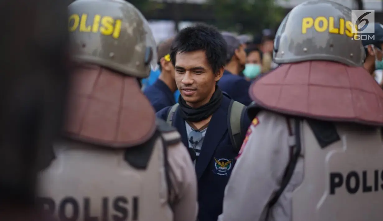 Massa dari Badan Eksekutif Mahasiswa Seluruh Indonesia (BEM SI) bersalaman dengan polisi saat aksi unjuk rasa di sekitar DPR RI, Jakarta, Selasa (1/10/2019). Selain berorasi secara damai, para mahasiswa membagikan bunga untuk para polisi yang mengawal aksi mereka. (Liputan6.com/Immanuel Antonius)