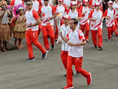 Presiden Joko Widodo didampingi Menpora Imam Nahrawi membawa api obor Asian Games 2018 sebelum upacara penurunan Bendera Merah Putih di Istana Negara Jakarta, Jumat (17/8). (Liputan6.com/Pool/Eko)
