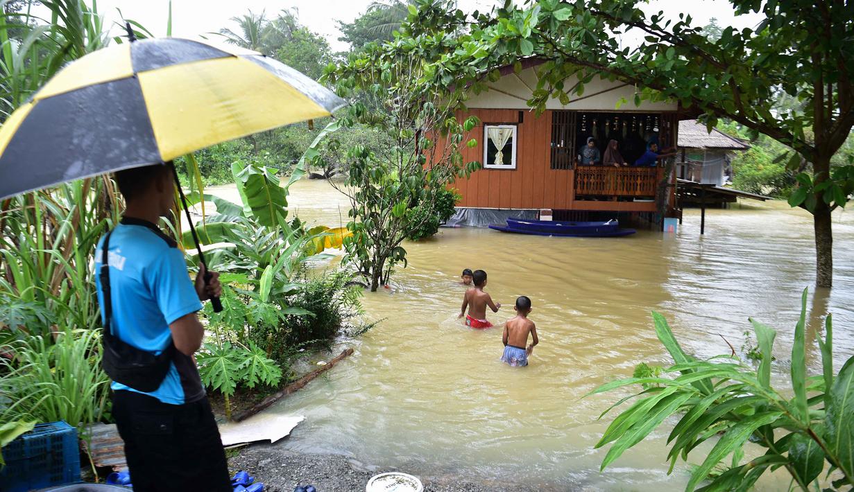 Dinas kedaruratan Thailand menyampaikan bahwa banjir berdampak pada lebih dari 2 juta orang, dengan banjir di Hat Yai dilaporkan merupakan yang terburuk dan berdampak pada 250.000 lebih keluarga. Tampak dalam foto, anak-anak bermain di tengah banjir di daerah Ban Yakang, distrik Mueang, provinsi Narathiwat, Thailand selatan, pada Selasa 25 November 2025. (Madaree TOHLALA/AFP)