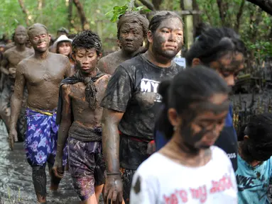 Warga Bali berjalan bersama dengan badan penuh lumpur saat mengikuti mandi lumpur tradisional atau yang dikenal sebagai Mebuug-buugan di desa Kedonganan, Bali (18/3). (AFP/Sony Tumbelaka)