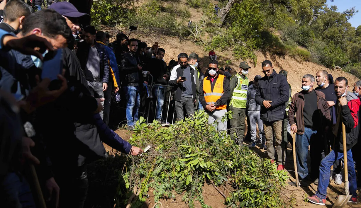Orang-orang berdiri di samping makam Rayan Oram (5) saat pemakamannya di Desa Ighran, Provinsi Chefchaouen, Maroko, 7 Februari 2022. Rayan Oram meninggal setelah terjebak selama lima hari dalam sumur kering sedalam 32 meter. (AP Photo/Mosa'ab Elshamy)