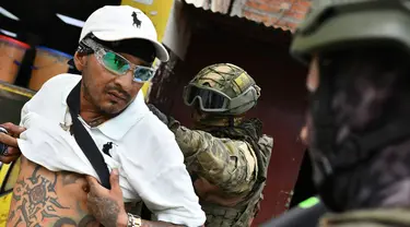 Tentara memeriksa punggung seorang pria untuk memeriksa tato geng selama operasi penghentian dan penggeledahan di Portoviejo, Ekuador, Kamis (11/1/2024). Presiden Ekuador Daniel Noboa pada Senin menetapkan keadaan darurat nasional karena gelombang kejahatan, sebuah tindakan yang memungkinkan pihak berwenang menangguhkan hak-hak masyarakat dan memobilisasi militer. (AP Photo/Ariel Ochoa)