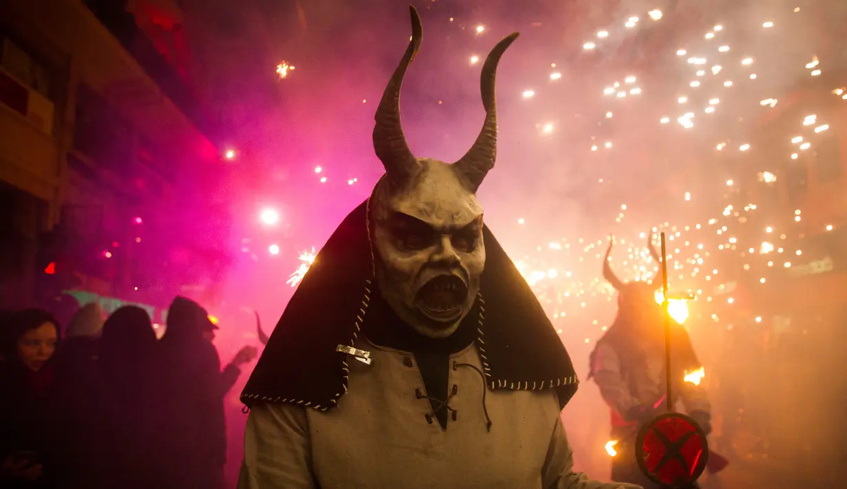 Seorang peserta bertopeng iblis menari dan bersuka ria dalam Festival Correfoc di Palma de Mallorca, Spanyol, Minggu (21/1). Correfoc adalah malam pesta pora di mana para peserta berpakaian seperti setan dan iblis. (AFP PHOTO/JAIME REINA)