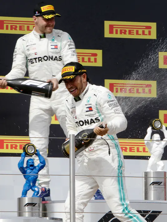 Pebalap Mercedes Lewis Hamilton (kanan) dan Valtteri Bottas berselebrasi dengan menyemprotkan sampanye saat menjuarai F1 GP Prancis 2019 di Sirkuit Paul Ricard, Minggu (23/6/2019). Hamilton tampil dominan dan menjadi juara F1 GP Prancis 2019. (AP Photo/Claude Paris)