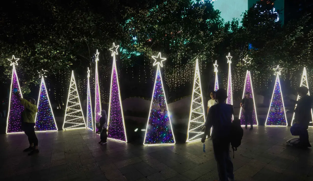 Jakarta Light Festival dijadwalkan berlangsung hingga Sabtu 27 Desember 2025 setiap pukul 18.00 hingga 22.00 WIB. Tampak dalam foto, warga menikmati suasana Jakarta Light Festival 2025 di sekitar Bundara Hotel Indonesia, Jakarta, Selasa (23/12/2025). (Kapanlagi.com/Budy Santoso)