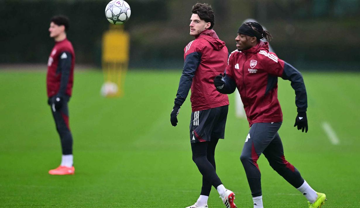 Di sisi lain, Kairat Almaty masih berupaya keras mencari poin perdana di kompetisi elite Eropa. Tampak dalam foto, gelandang Arsenal asal Inggris, Declan Rice (tengah) bersama Noni Madueke (kanan) mengikuti sesi latihan tim di pusat pelatihan Arsenal di London Colney, utara London, pada Selasa 27 Januari 2026. (Ben STANSALL/AFP)