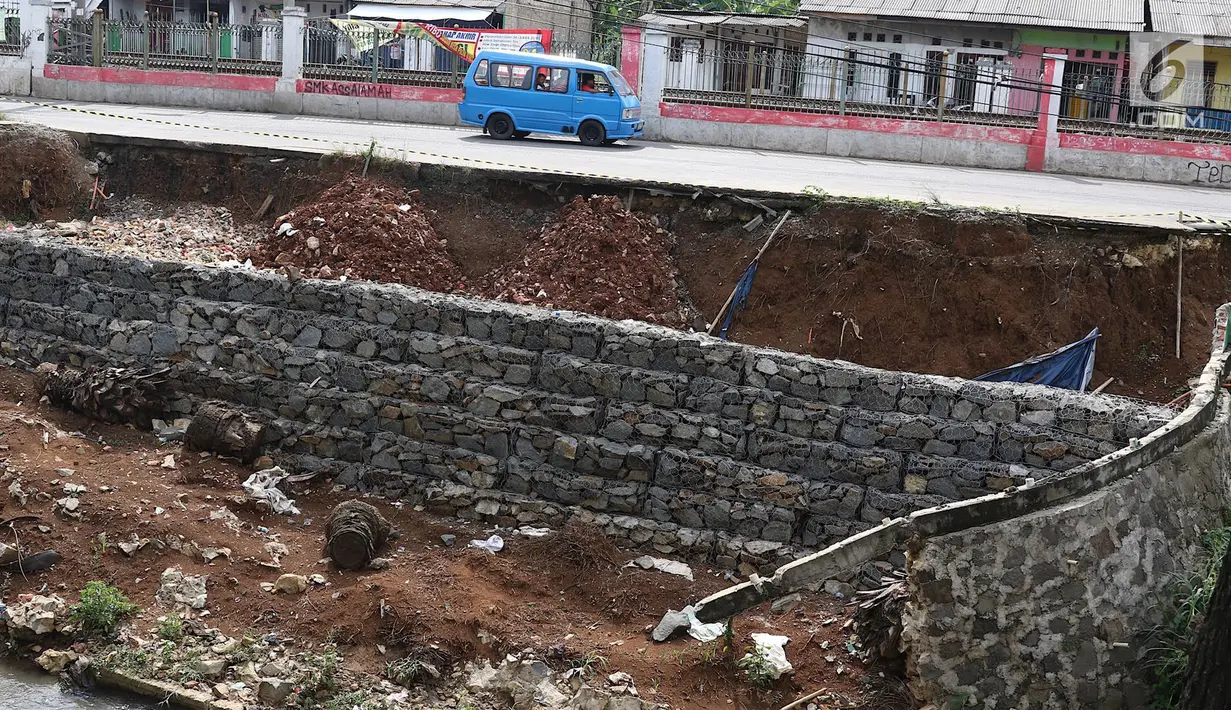 Kendaraan melintas di samping Jalan Raya Citayam yang amblas di kawasan Cipayung, Depok, Jawa Barat, Rabu (27/2). Kondisi tepi jalan yang tidak kunjung diperbaiki membahayakan pengguna jalan terutama saat malam hari. (Liputan6.com/Immanuel Antonius)