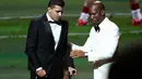 Pemain Manchester City, Rodri (kiri) dipapah oleh mantan pesepak bola, Didier Drogba saat menaiki panggung penghargaan Ballon d'Or 2024 pada acara yang berlangsung di Theatre du Chatelet, Paris, Selasa (29/10/2024) dini hari WIB. (AFP/Franck Fife)
