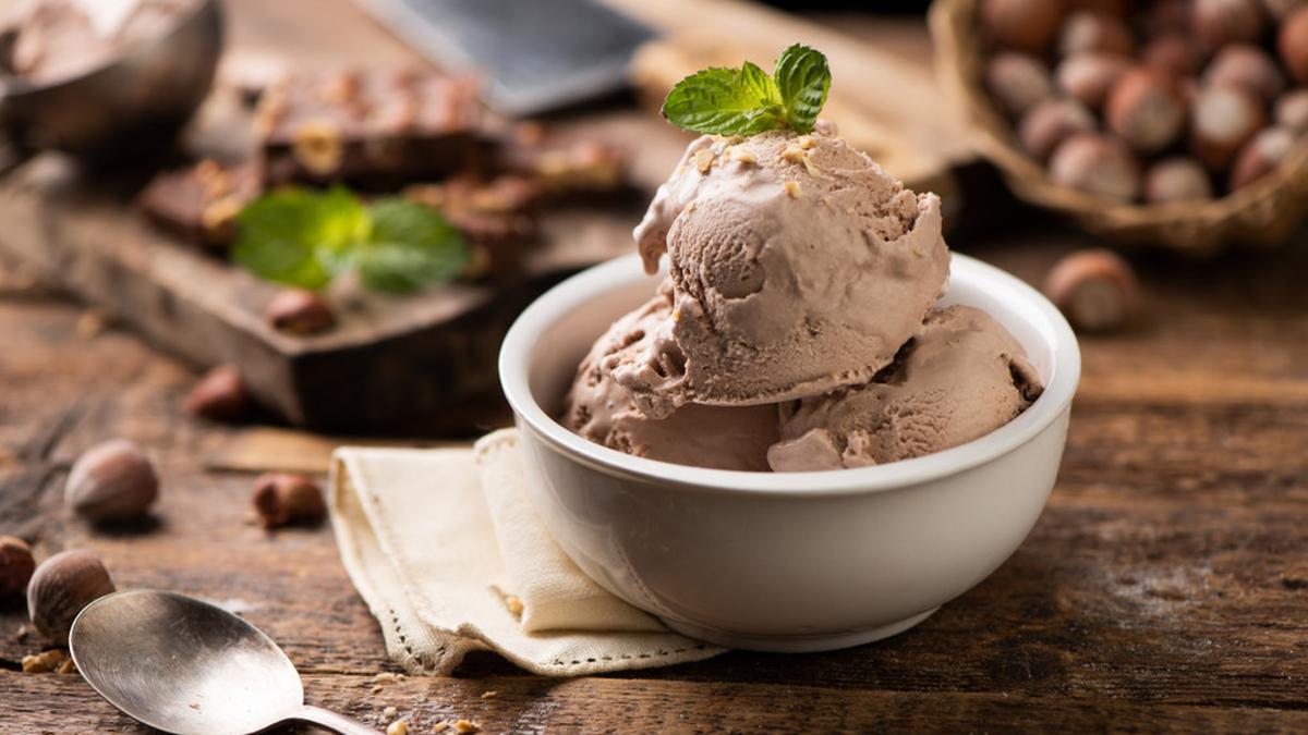 Es krim cokelat creamy dengan topping kacang almond dan saus cokelat leleh, sempurna untuk menyegarkan hari Anda