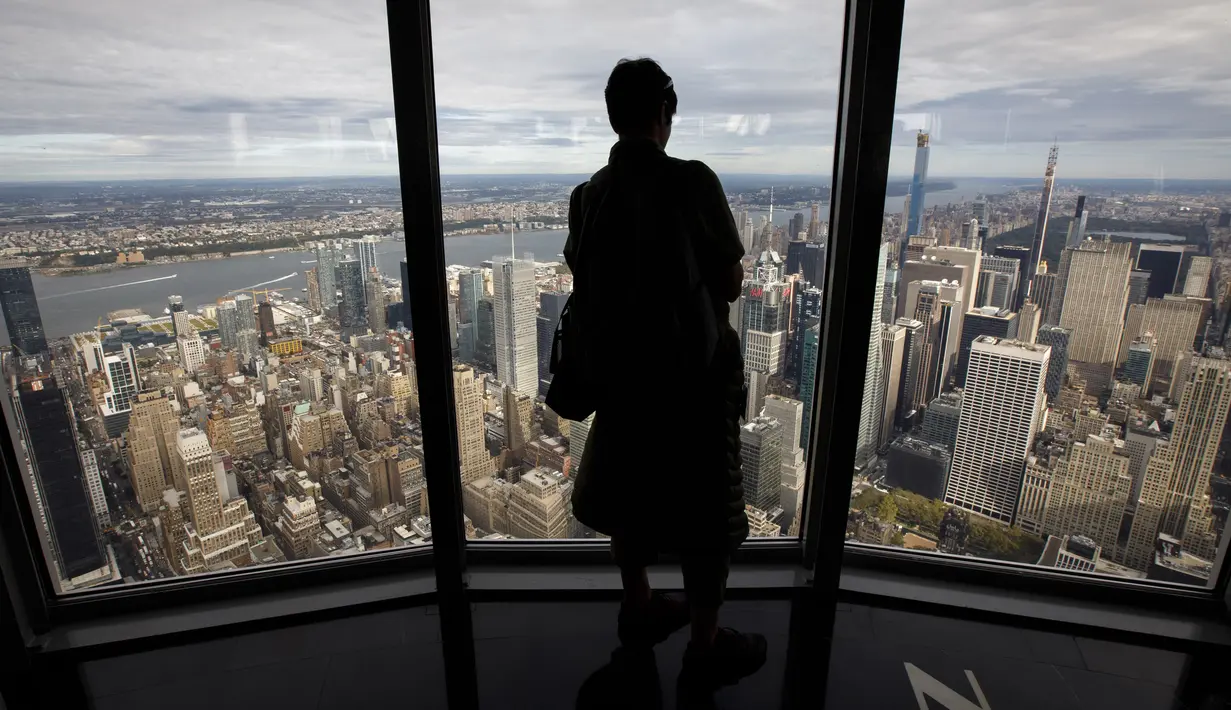 Seorang wanita menikmati pemandangan Kota Manhattan dari ruangan observatorium di lantai 102 Gedung Empire State yang baru direnovasi di New York (10/10/2019). Dibuka untuk umum pada 12 Oktober, ruang observatorium ini berjarak 1.250 kaki di atas permukaan jalan. (AFP Photo/Drew Angerer)