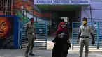 Polisi berjaga-jaga ketika seorang siswa sekolah menengah negeri dan perguruan tinggi pra-universitas untuk wanita melangkah keluar untuk mengembalikan telepon kepada orang tuanya yang berdiri di luar tempat institut pendidikan di Bangalore (16/2/2022). (AFP/Manjunath Kiran)
