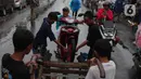 Warga mengangkut sepeda motor menggunakan gerobak melintasi banjir di jalan KH Hasyim Ashari, Kota Tangerang, Banten, Sabtu (16/7/2022). Warga sekitar membantu para pengendara yang melintas agar tidak terkena banjir dengan menawarkan jasa gerobak. (Liputan6.com/Angga Yuniar)