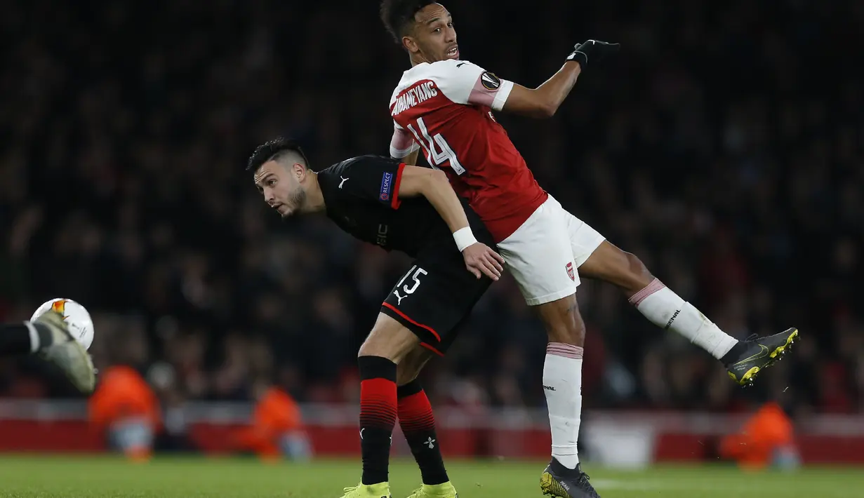 Duel udara antara Aubameyang dan Rami Bensebaini pada leg kedua,babak 16 besar Liga Europa yang berlangsung di Stadion Emirates, London, Jumat (15/3). Arsenal menang 3-0 atas Rennes. (AFP/Ian Kington)