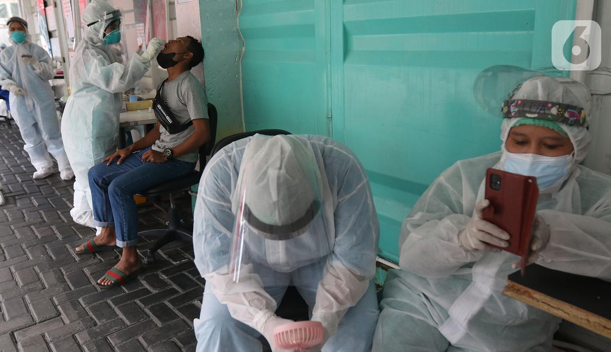 Petugas kesehatan beristirahat ketika rekannya melakukan tes usap (swab test) PCR di Jakarta, Senin (25/10/2021). Presiden Joko Widodo atau Jokowi mengarahkan untuk menurunkan harga tes PCR menjadi Rp300 ribu dan masa berlaku diperpanjang 3x24 jam.  (Liputan6.com/Herman Zakharia)