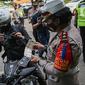 Petugas kepolisian lalu lintas mengecek STNK pengendara motor saat Operasi Zebra Jaya 2020 di kawasan Cawang, Jakarta, Senin (26/10/2020). Operasi Zebra Jaya dilaksanakan pada 26 Oktober-8 November 2020 untuk menekan jumlah pelanggaran lalu lintas. (Liputan6.com/Faizal Fanani)