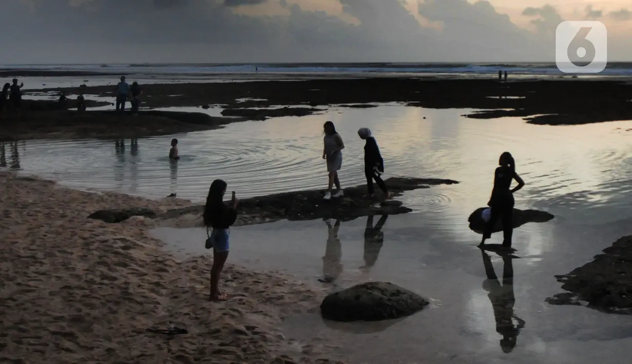 Wisatawan menikmati kolam renang alami yang terbentuk saat air laut surut di kawasan Pantai Suluban, Uluwatu, Bali, Selasa (7/9/2021). Keunikan Pantai Suluban dengan kolam-kolam yang terbentuk di atas karang menjadi daya tarik wisatawan. (merdeka.com/Arie Basuki)