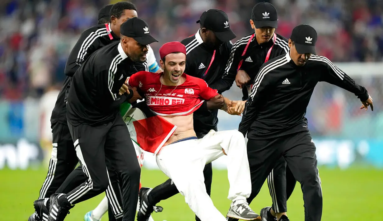Petugas keamanan membawa penyusup lapangan pada pertandingan sepak bola Grup D Piala Dunia 2022 antara Tunisia dan Prancis di Education City Stadium, Al Rayyan, Qatar, 30 November 2022. Mengenai aksi tersebut, banyak warganet yang memberikan pujian. (AP Photo/Martin Meissner)