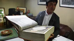 Seorang seniman Afghanistan, Abdull Sabur Omari menunjukkan Alquran buatan tangan di Mourad Khani, Kabul, Afghanistan (19/4). Kitab suci Alquran ini dibuat dengan tangan secara manual di atas kain sutra. (AFP/Wakil Kohsar)