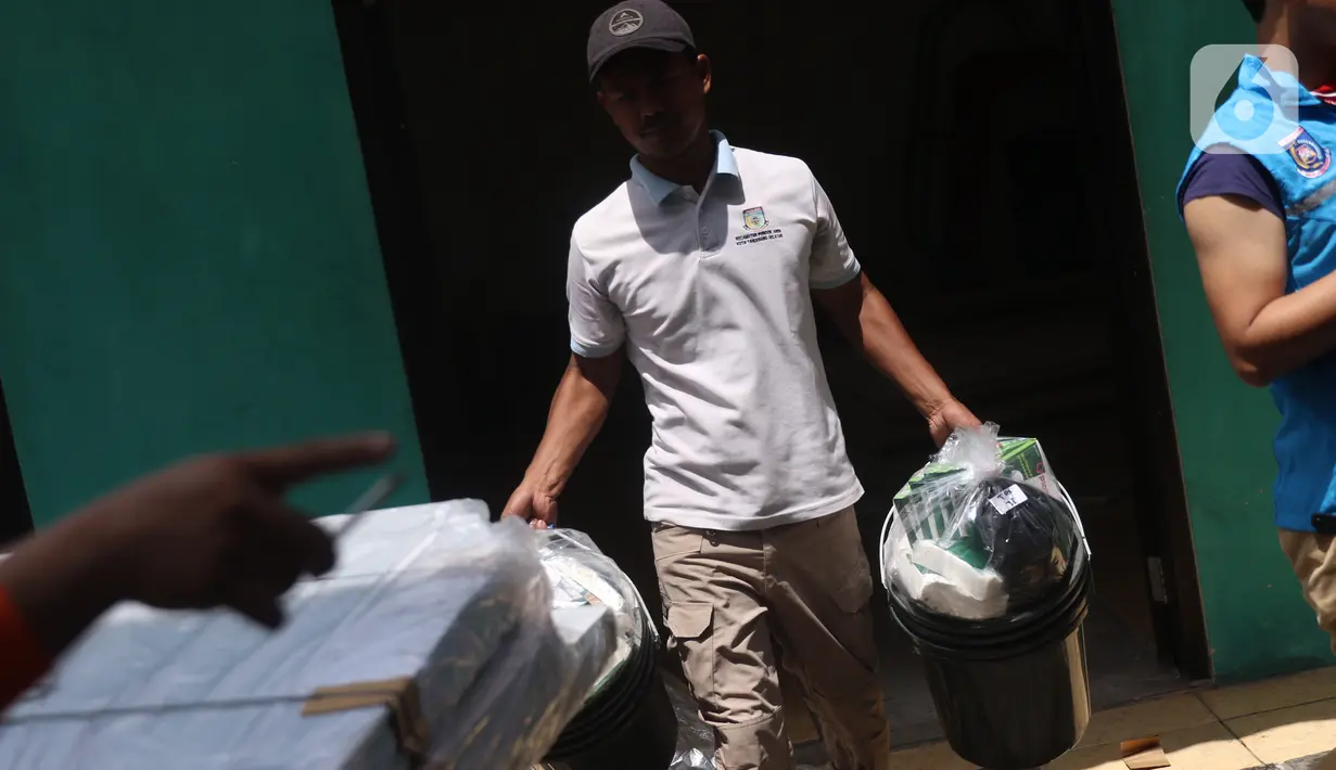 Petugas Panitia Pemungutan Suara (PPS) mendistribusikan alat pelindung diri (APD) untuk setiap TPS di Parigi, Tangerang Selatan, Selasa (8/12/2020). PPS juga menyiapkan APD seperti masker, sarung tangan, baju hazmat, ember pencuci tangan untuk keperluan Pilkada Tangsel. (Liputan6.com/Angga Yuniar)