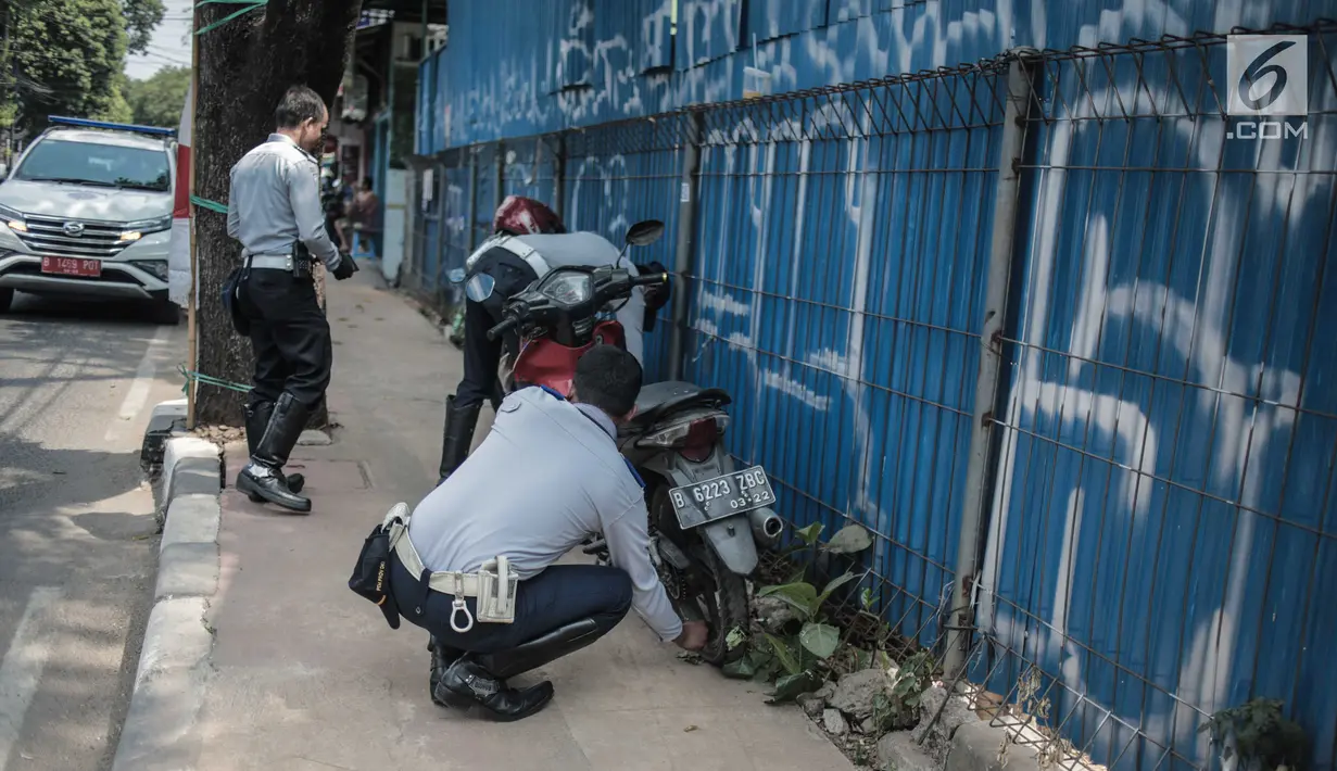 Petugas Dishub DKI Jakarta merazia  kendaraan roda dua dengan mencopot pentil yang terparkir di trotoar di kawasan Cipete Raya, Jakarta, Selasa (13/8/2019). Razia tersebut dilakukan Dishub untuk mengembalikan fungsi trotoar untuk pejalan kaki. (Liputan6.com/Faizal Fanani)