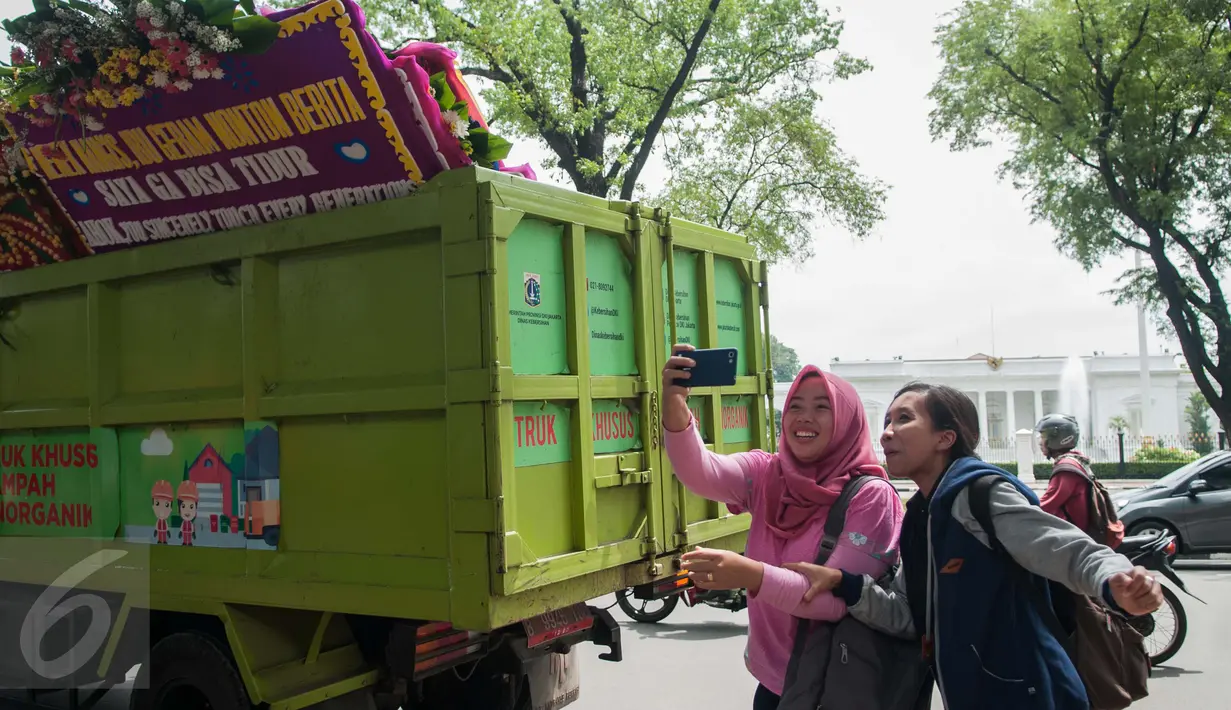 Warga berswafoto di dekat karangan bunga untuk Gubernur dan Wakil Gubernur DKI Jakarta Basuki T Purnama (Ahok) dan Djarot Syaiful Hidayat di Balai Kota Jakarta, Rabu (28/4). (Liputan6.com/Gempur M Surya)