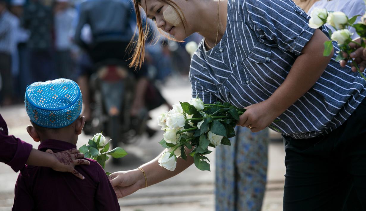 Umat Buddha Myanmar membagikan mawar putih kepada seorang bocah Muslim setelah melaksanakan salat Id pada perayaaan Idul Fitri di kota Than Lyin, Yangon, Rabu (5/6/2019). Relawan berbaris di luar masjid dan memberikan bunga itu kepada jemaah yang merayakan Idul Fitri. (Sai Aung MAIN/AFP)