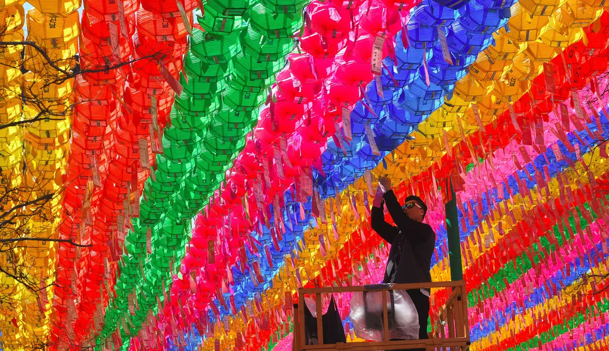 Pengunjung memasang kartu harapan di salah satu lampion di Jogye Temple jelang perayaan ulang tahun Buddha, Seoul, Rabu (12/4). Di Negeri Ginseng ini, ulang tahun Buddha dirayakan dengan menggelar ‘Lotus Lantern Festival’. (AFP PHOTO / JUNG Yeon-Je) 