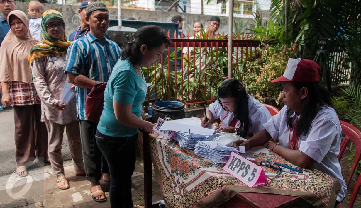 Petugas KPPS berseragam sekolah dasar melayani warga yang ikut berpartisipasi dalam pelaksanaan Pilkada DKI 2017 di TPS 45 Kelurahan Kebon Pala, Jakarta, Rabu (15/2). Hal itu dilakukan untuk menarik warga datang ke TPS. (Liputan6.com/Gempur M Surya)