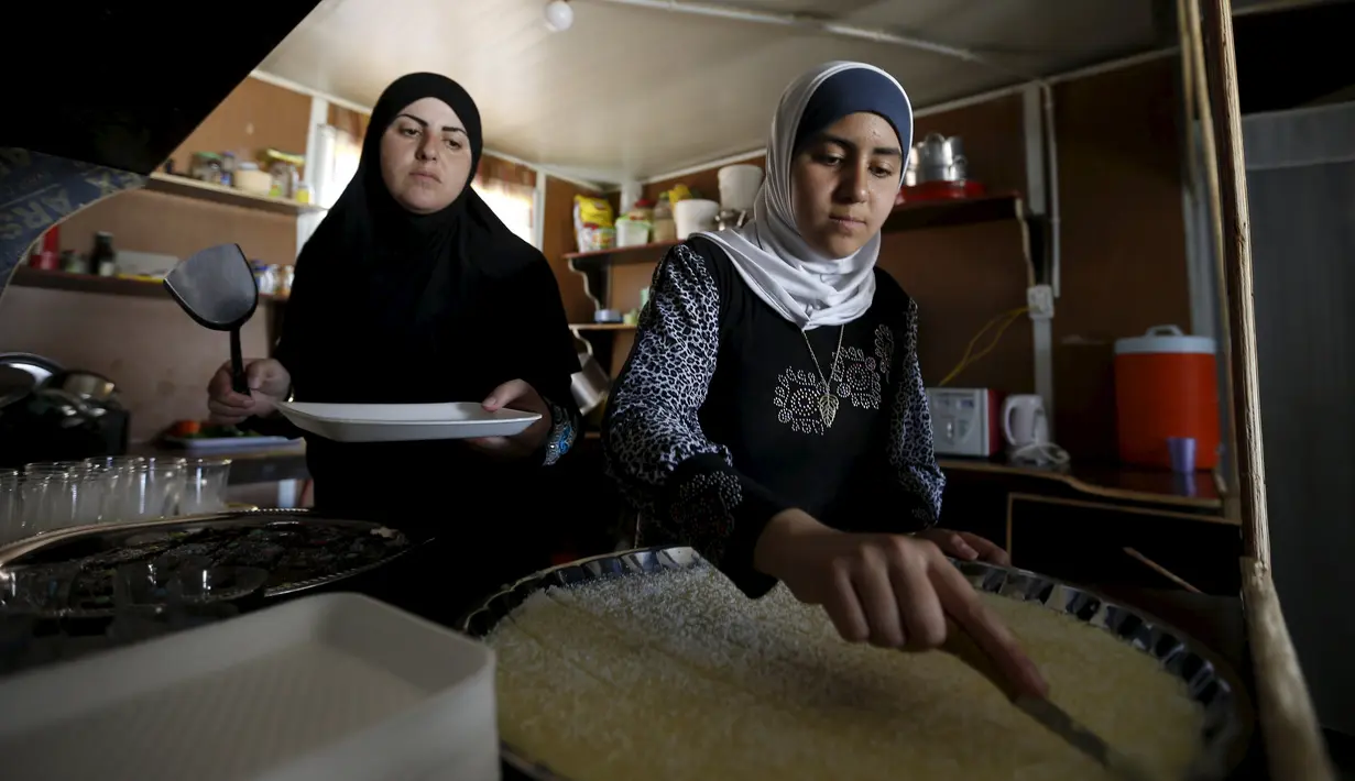 Omayma membantu ibumya memasak di rumahnya di kamp pengungsi Al Zaatari, Mafraq, Yordania (21/4). Meski berusia 14 tahun, Omayma sangat aktif menyerukan perlawanan terhadap pernikahan dini yang marak di Suriah. (REUTERS / Muhammad Hamed)