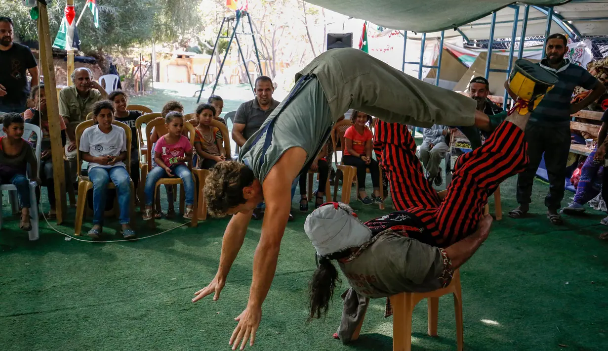 Anak-anak Palestina menyaksikan atraksi badut Spanyol di desa suku Bedouin, Tepi Barat yang diduduki, 22 September 2018. Atraksi ini dilakukan lantaran desa berpenduduk sekitar 180 orang itu akan digusur Israel pada Oktober mendatang. (AFP/ABBAS MOMANI)