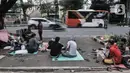 Kendaraan melintas di dekat imigran pencari suaka yang menghuni di depan Kantor UNHCR Kebon Sirih, Jakarta, Kamis (1/4/2021). Puluhan imigran dari berbagai negara konflik kembali menghuni di depan Kantor UNHCR Kebon Sirih sejak beberapa waktu lalu. (merdeka.com/Iqbal S Nugroho)