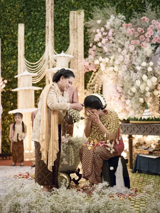Dalam kesempatan ini, iriana Jokowi dan Sofiatun Gudono tampil dengan kebaya yang cukup kontras. Iriana dengan kebaya kutubaru berwarna kuning cerah dan ditambah aksen selendang warna senada. Ia melengkapi kebayanya dengan kain batik warna coklat. [@erinagudono/@shaniagudono].