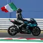 Pembalap Petronas Yamaha, Franco Morbidelli, melakukan selebrasi dengan mengibarkan bendera Italia usai menjuarai MotoGP San Marino di Sirkuit Misano, Minggu (13/9/2020). Morbidelli menjadi yang tercepat dengan catatan waktu 42 menit 02,272 detik. (AP/Antonio Calanni)