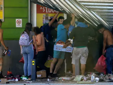 Warga menjarah sebuah supermarket di Puente Alto, wilayah metropolitan Santiago, Chile, Minggu (20/10/2019). Bentrokan pecah di Santiago setelah dua orang tewas ketika sebuah supermarket dibakar ketika protes terhadap kondisi ekonomi dan ketidaksetaraan sosial. (DRAGOMIR YANKOVIC/ATON CHILE/AFP)