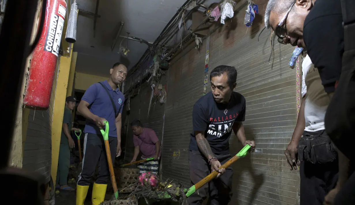 Para pria membersihkan sisa-sisa banjir di Badung, Bali, pada Jumat 12 September 2025. (AP Photo/Firdia Lisnawati)
