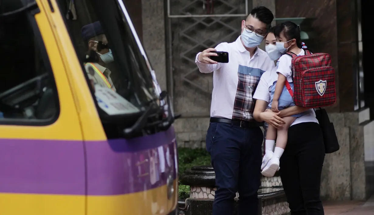Seorang anak berfoto dengan orang tuanya sebelum menaiki bus sekolah di Hung Hom, Hong Kong, China selatan, pada 29 September 2020. Aturan menjaga jarak sosial (social distancing) sebagian telah dilonggarkan dan kehidupan masyarakat mulai kembali normal. (Xinhua/Wang Shen)