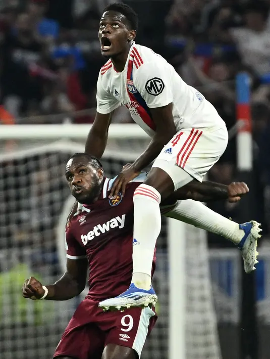Bek Olympique Lyon Castello Lukeba (atas) berebut bola dengan gelandang West Ham United Michail Antonio pada leg kedua perempat final Liga Europa melawan Lyon di Parc Olympique Lyonnais, Jumat (15/4/2022) dini hari WIB. West Ham lolos ke semifinal usai melibas tuan rumah Lyon 0-3. (Jeff PACHOUD/AFP)