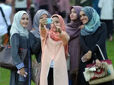 Warga berfoto selfie usai melaksanakan Salat Idul Fitri 1437 H di Kebun Raya Bogor, Rabu (6/7). Pemerintah Kota Bogor menyelenggarakan Salat Idul Fitri 1437 H yang dipusatkan di areal Kebun Raya. (Liputan6.com/Helmi Fithriansyah) 