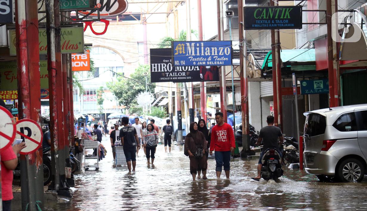 Warga melintas di kawasan pertokoan Pasar Baru, Jakarta, Kamis (2/1/2020). Pasca banjir yang melanda sejumlah titik di Jakarta pada Rabu (1/1), aktivitas perniagaan di kawasan Pasar Baru masih terlihat sepi dan sebagian toko masih tutup. (Liputan6.com/Helmi Fithriansyah)