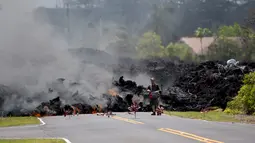 Seorang lelaki mengambil gambar lava pijar erupsi Gunung Kilauea yang menutupi jalan di Pahoa, Hawaii, Amerika Serikat, Sabtu (5/5). Aliran lava pijar membakar apa saja yang berada di sekitarnya. (AP Photo/Marco Garcia)