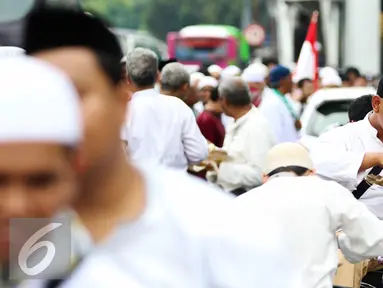 Sejumlah massa aksi makan siang sebelum memulai aksi di Medan Merdeka Timur, Jakarta, Jumat (4/11). Massa melakukan aksi di depan Istana Negara menuntut penegakan hukum kasus dugaan penistaan agama. (Liputan6.com/Faizal Fanani)