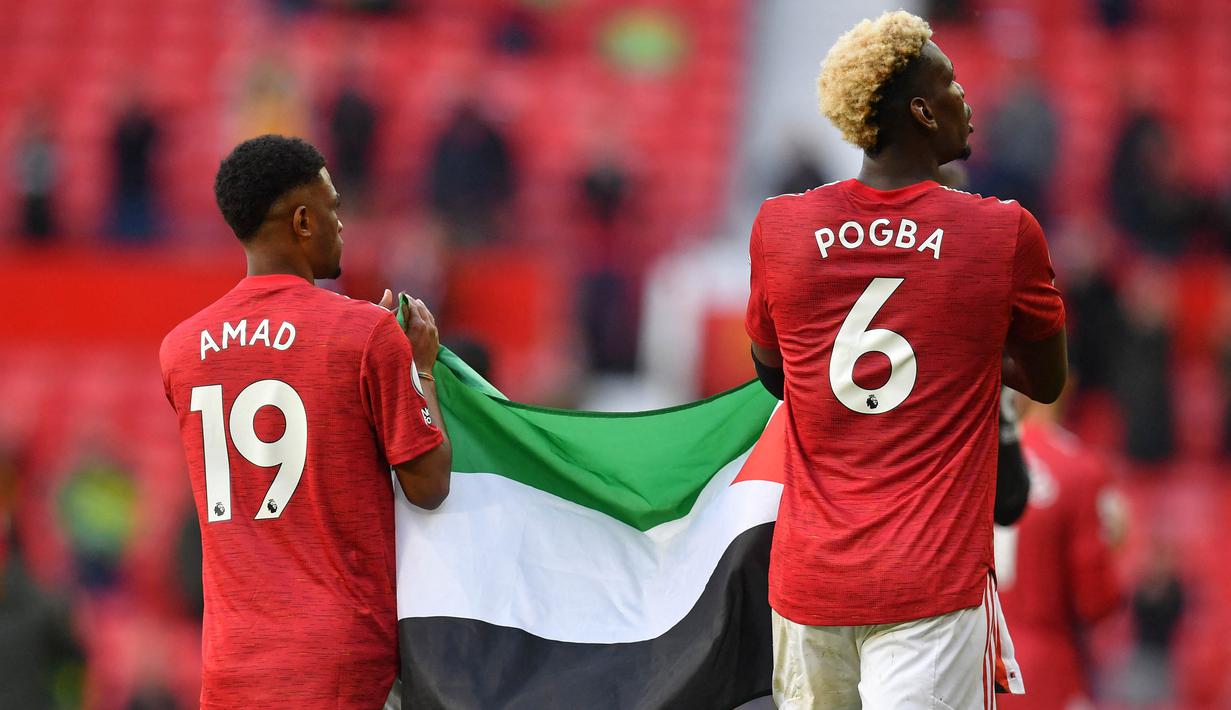 Dua pemain muslim Manchester United, Paul Pogba dan Amad Diallo, membentangkan bendera Palestina di markas Manchester United, yaitu Stadion Old Trafford. (Foto: AFP/Pool/Paul Ellis)