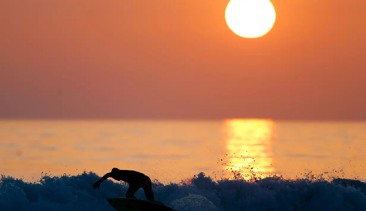 Seorang pria berselancar saat matahari terbenam di sebuah pantai di La Serena, Chile, Selasa (23/5/2015). (REUTERS/Marcos Brindicci)