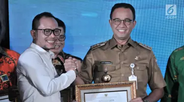 Gubernur DKI Jakarta Anies Baswedan (kanan) menerima penghargaan dari Menteri Ketenagakerjaan Hanif Dhakiri (kiri) dalam Indeks Pembangunan Ketenagakerjaan (INTEGRA) 2018 di Kantor Kemnaker, Jakarta, Senin (19/11). (Merdeka.com/Iqbal Nugroho)