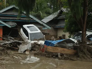 Kendaraan hanyut oleh banjir bandang di sebelah rumah-rumah di desa Radda di Kabupaten Luwu Utara, Sulawesi Selatan (14/7/2020). Hujan lebat yang mengakibatkan tiga sungai meluap telah menyapu rumah-rumah, kendaraan dan berbagai fasilitas umum di enam kecamatan di Kabupaten Luwu Utara. (AFP/Aryanto)