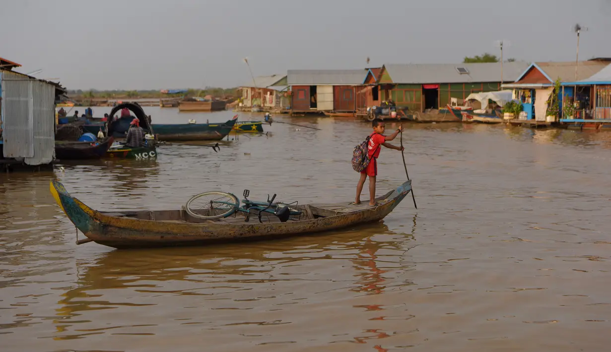 Seorang anak laki-laki mendayung perahu di sungai Siem Reap di Siem Reap, Kamboja (5/12/2019). Sungai Siem Reap adalah sungai yang mengalir melalui Provinsi Siem Reap, di barat laut Kamboja. (AFP/Manan Vatsyayana)